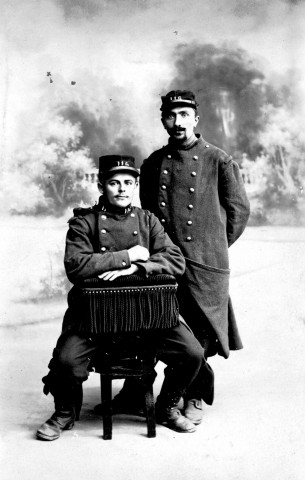 [Deux soldats du 116e régiment d'infanterie posent en uniforme dans un atelier de photographie, dont Julien Bernier (assis)]. - [s.l.], [vers 1917-1919?]