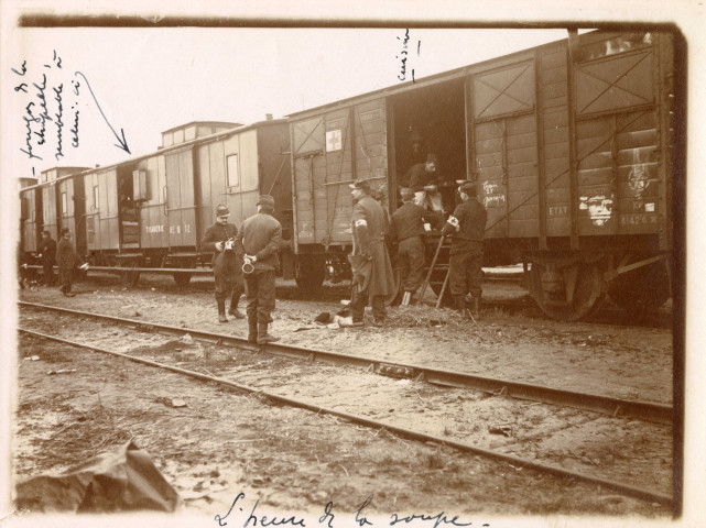 Huit hommes devant des wagons, deux tiennent leur "gamelle"