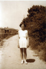 Jeune fille sur un chemin de la cité provisoire, plusieurs bungalows en arrière plan.