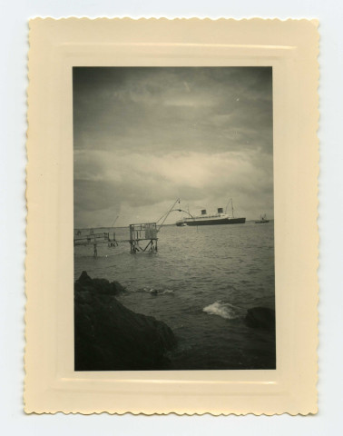 Paquebot "Liberté" en mer au large de Saint-Nazaire [au cours d'essais en mer ou de son départ pour Le Havre]. Au premier plan des pêcheries à Saint-Nazaire.