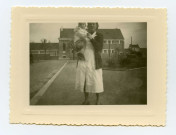 Simone Toussaint portant une jeune enfant devant l'Ecole Jean-Jaurès boulevard Victor-Hugo.