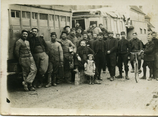 Soldats adossés à des camions posant près d'une petite fille dont Antoine Depuntis posant sur un vélo. - [1914-1915]