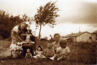 Trois enfants posant avec leurs jouets, en arrière plan des bungalows.