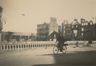 Maisons situées devant la gare au fond la base sous-marine, au premier plan un homme en vélo.