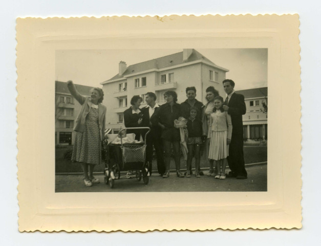 Portrait familial : 10 personnes posent devant un immeubles dont deux enfants et un nourisson dans un landau. A gauche, Simone Toussaint.
