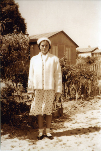 Femme posant sur un chemin de la cité provisoire, avec des bungalows en arrière plan