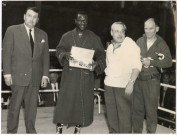 Souleymane Diallo montre la ceinture tricolore de champion de France, entouré de son entraîneur Yvon Quéfféléan et de deux autres personnalités.