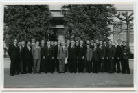 Groupe de 27 hommes posant devant un bâtiment