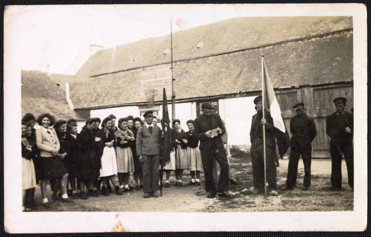 Cérémonie patriotique : groupe de personnes autour d'un drapeau (lieu inconnu). Un homme lit un texte.